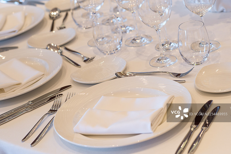 优雅的白色瓷器和玻璃器皿的正式餐桌布置图片素材