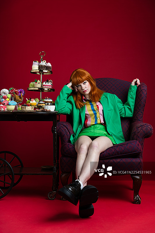 身着绿色套装的时尚女子与精心布置的甜点展示图片素材