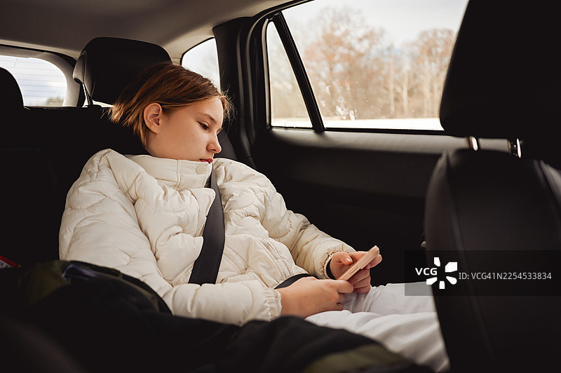 坐在后座的青少年看着手机图片素材