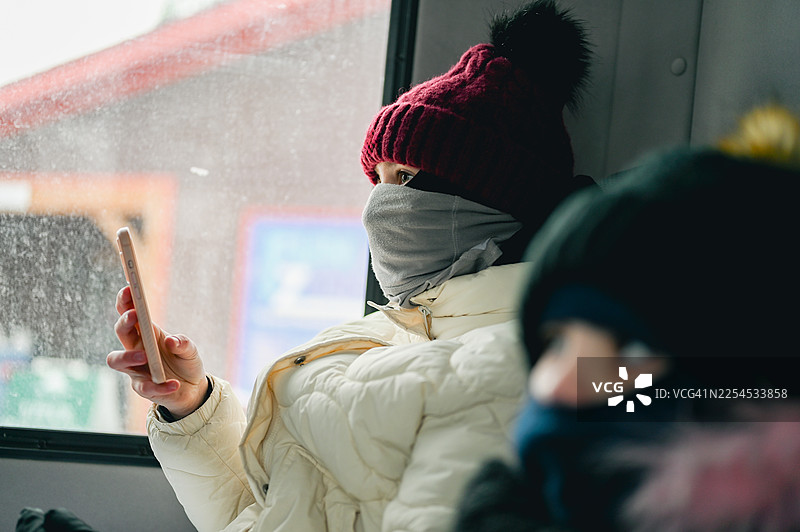 穿着冬外套和颈套的少女在公交车上旅行图片素材