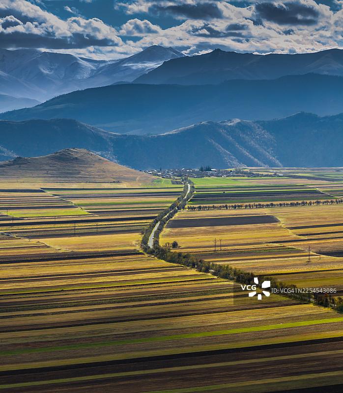 从空中俯瞰亚美尼亚洛里省附近，在戏剧般的光线和云影下，可以看到农田和山脊形成的图案。图片素材