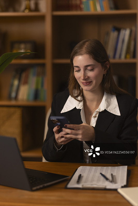 女子边工作边用手机查看社交媒体图片素材