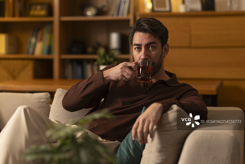 男人在家里的沙发上放松地喝着热茶图片素材