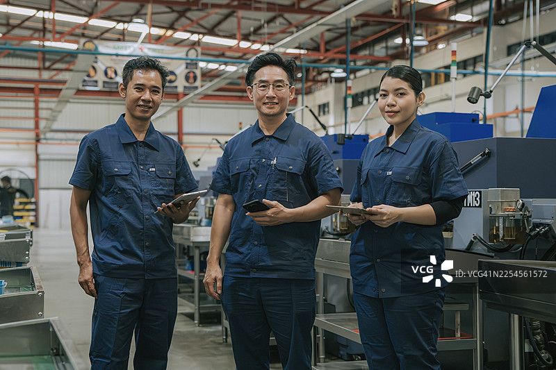 亚洲工厂工人在现代化工厂使用数码设备的团队肖像图片素材