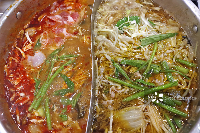 双味亚洲火锅，包含泰式冬阴功辣汤和清汤锅底，配有猪肉和什锦蔬菜图片素材