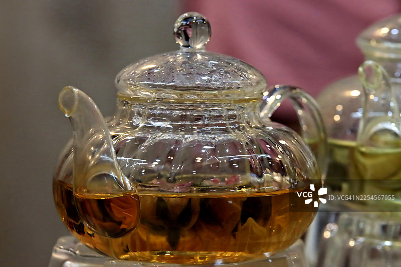 带保温器的优质有机花草茶透明茶壶，象征健康生活和水疗概念图片素材