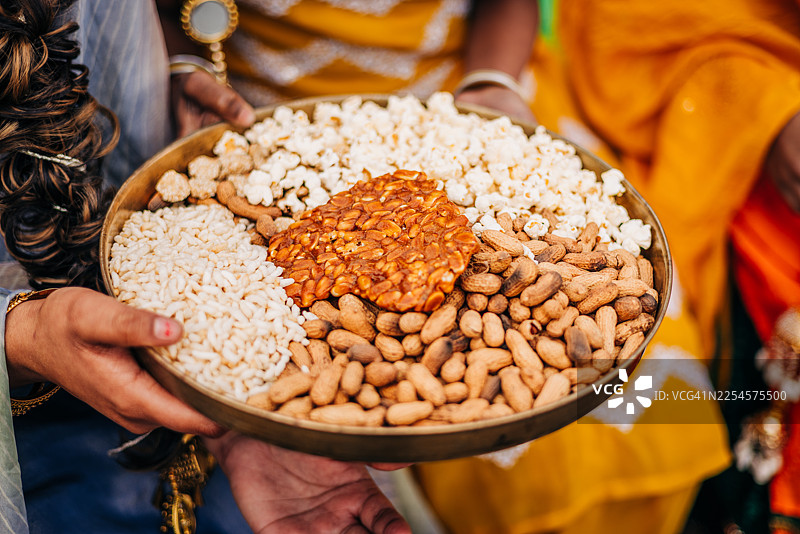 洛赫里节：手捧传统洛赫里零食——花生、爆米花、Rewari 和 Gajak图片素材