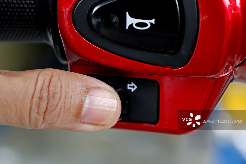 特写：手指按下摩托车转向灯开关，以安全地变道图片素材