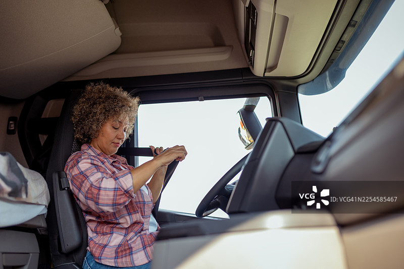 女卡车司机在驾驶室里系安全带图片素材