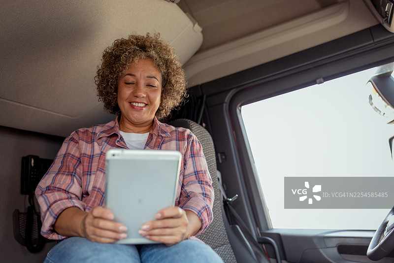 一位微笑的女卡车司机在休息站停车时使用平板电脑图片素材