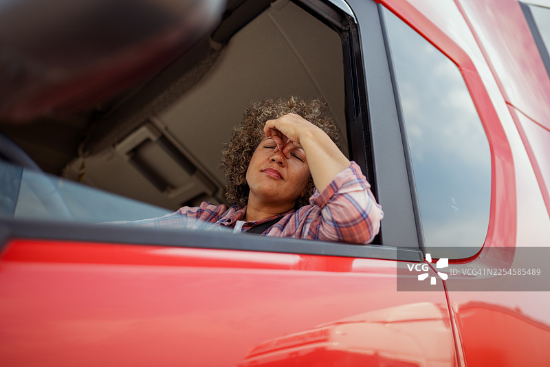 女卡车司机坐在驾驶座上，头痛发作图片素材