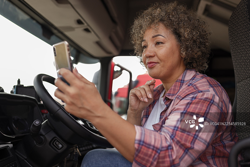 女性卡车司机在商用货车内部使用智能手机图片素材