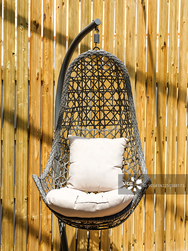 带靠垫的柳条蛋形吊椅，置于后院图片素材