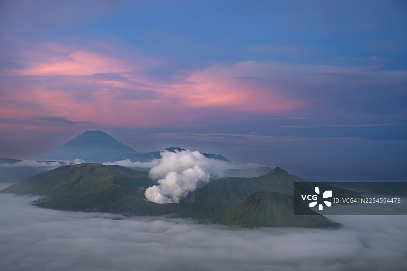 印度尼西亚东爪哇，布罗莫火山在黎明时分，笼罩在薄雾和烟雾之中，天空呈现粉色图片素材