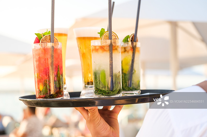 服务员托盘上放着夏日鸡尾酒和啤酒图片素材