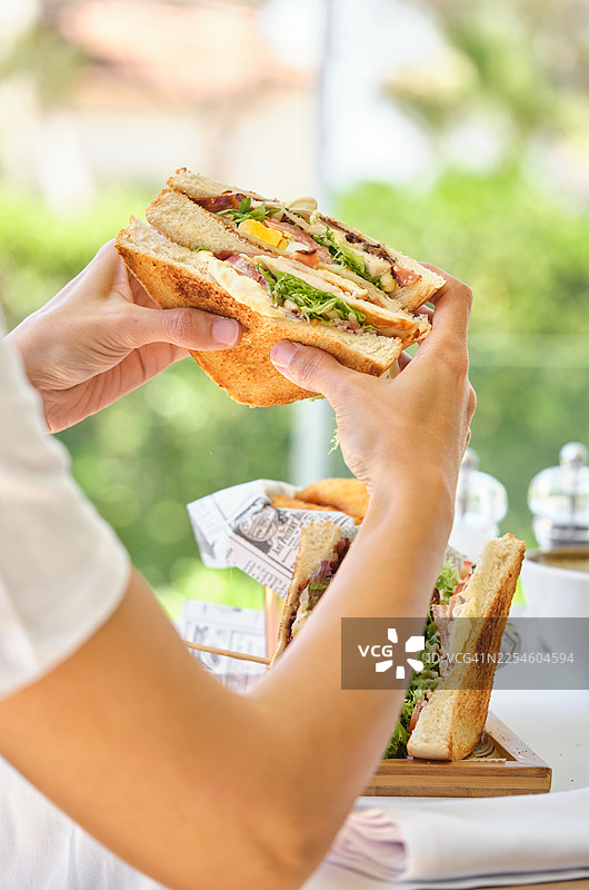 户外手持培根鸡蛋俱乐部三明治图片素材