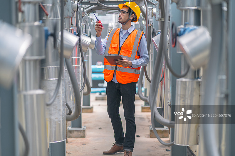 工程师佩戴安全装备，检查工业管道以进行质量控制。能源行业的生产力和效率评估正在进行中。图片素材