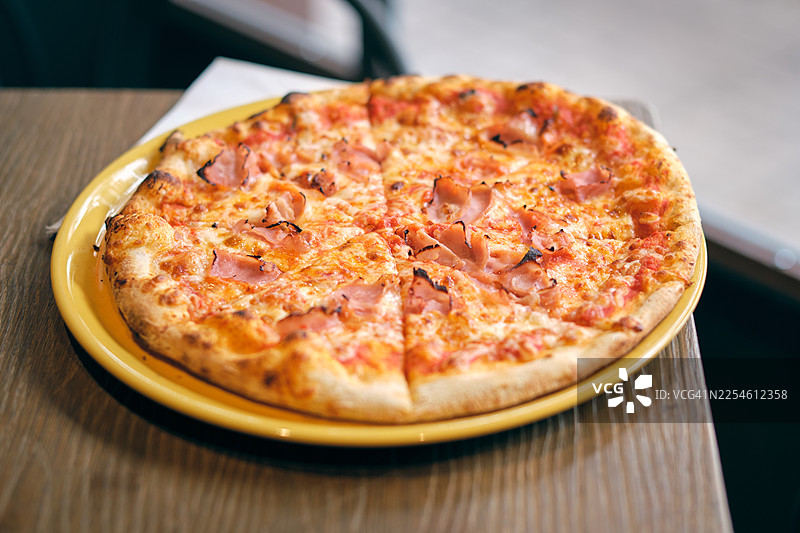 在黄色盘子上切火腿芝士披萨图片素材