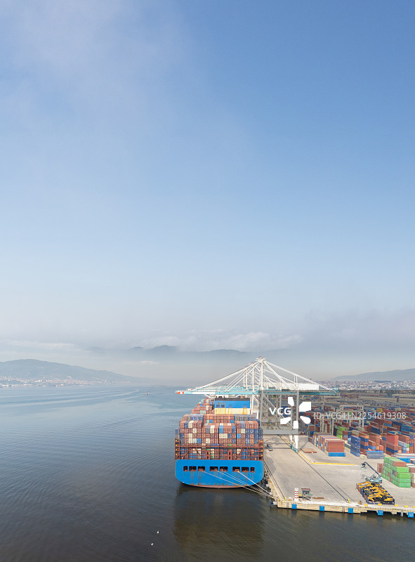 大型集装箱货轮装载着集装箱停靠在国际港口的鸟瞰图图片素材