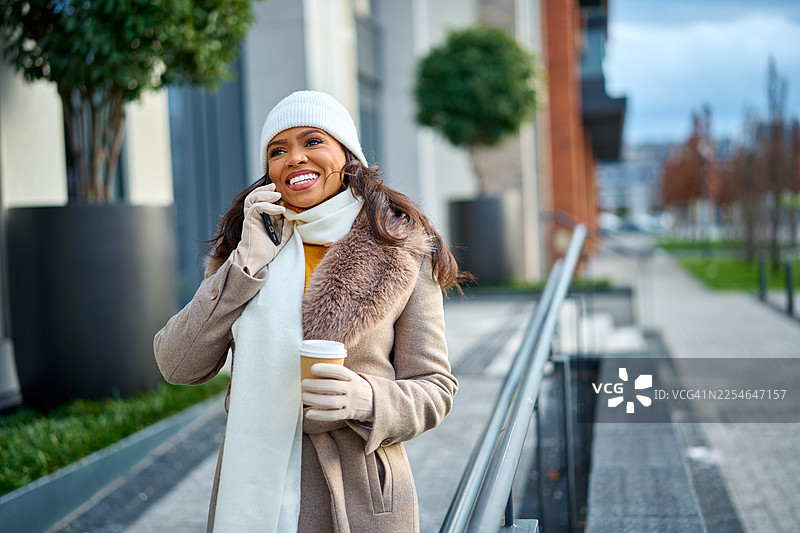 女人在城市里一边喝咖啡一边打电话图片素材