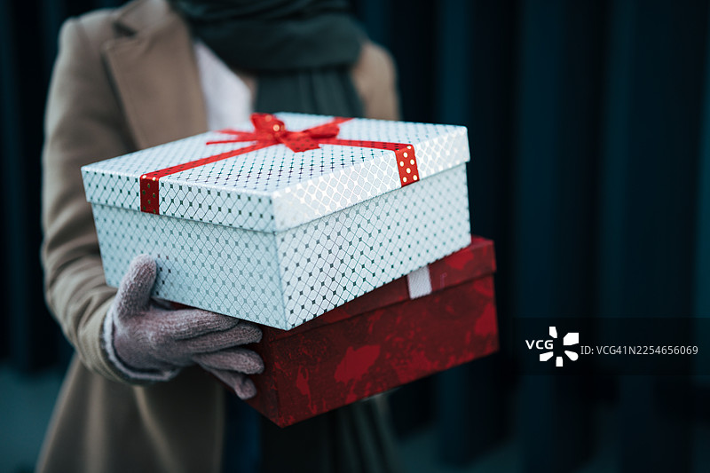 节日期间，一个人拿着两个包装好的礼品盒图片素材