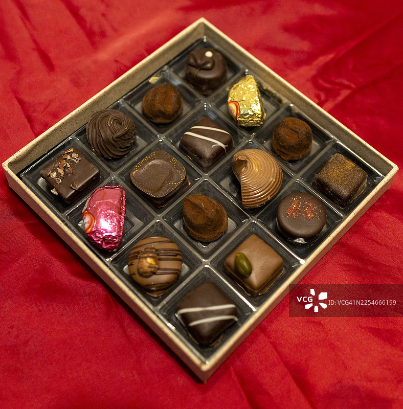 红色织物上各种口味和质地的巧克力松露特写图片素材