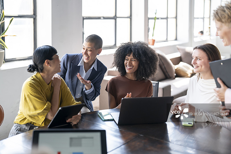 快乐的女商人在现代办公室里协作处理项目图片素材