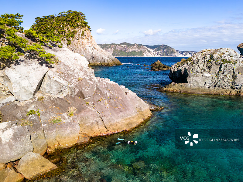 无人机航拍，人们在丸根滨海滩的表面游泳和攀爬悬崖，海面上可以看到被称为“白妈妈悬崖”的新岛白垩纪悬崖以及无人居住的半岛岛，并获得了许可。图片素材