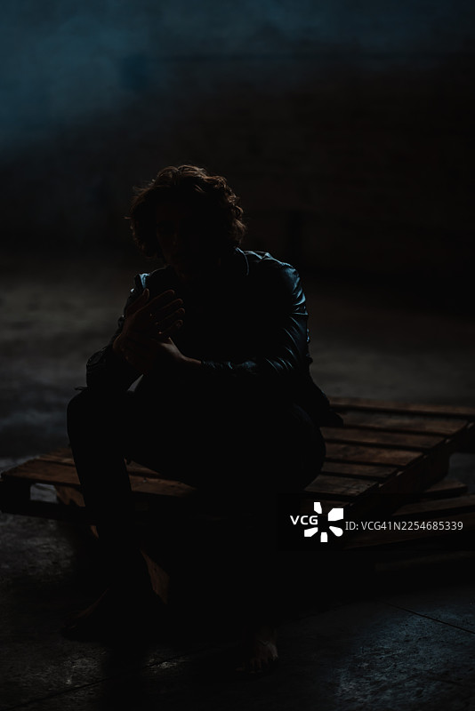 仓库背景下独自沉思的年轻男子图片素材