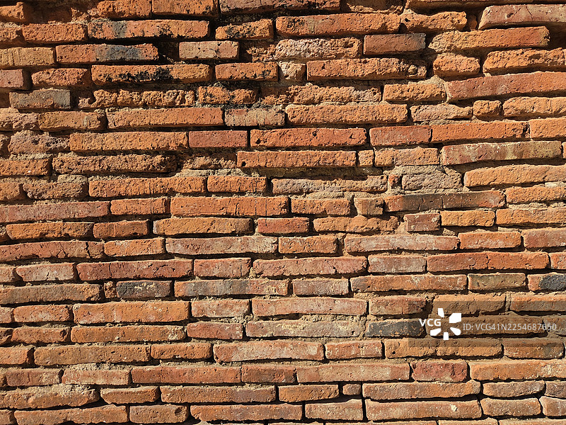 棕色砖块砌体墙展示图案堆叠砖块粗糙表面纹理材质背景，接缝处用红色水泥砂浆填充图片素材