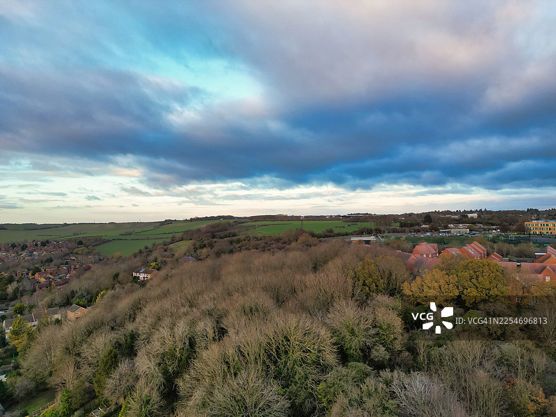 英国卢顿，诺尔山景区的空中俯瞰，展现了起伏的山丘、零散的房屋以及蓝灰云朵交织的戏剧性天空图片素材