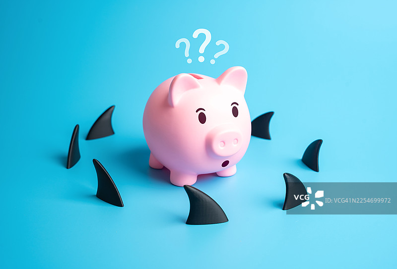 一只惊讶的粉色储蓄罐被鲨鱼鳍包围着，背景是鲜艳的蓝色，象征着金融风险和不确定性图片素材