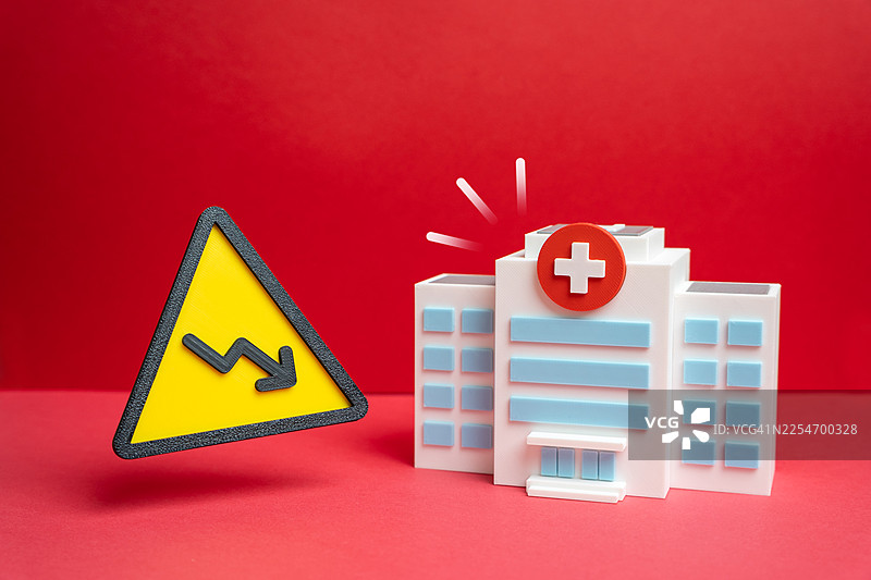 带有衰退警示标志的微型医院建筑，背景为鲜艳的红色图片素材