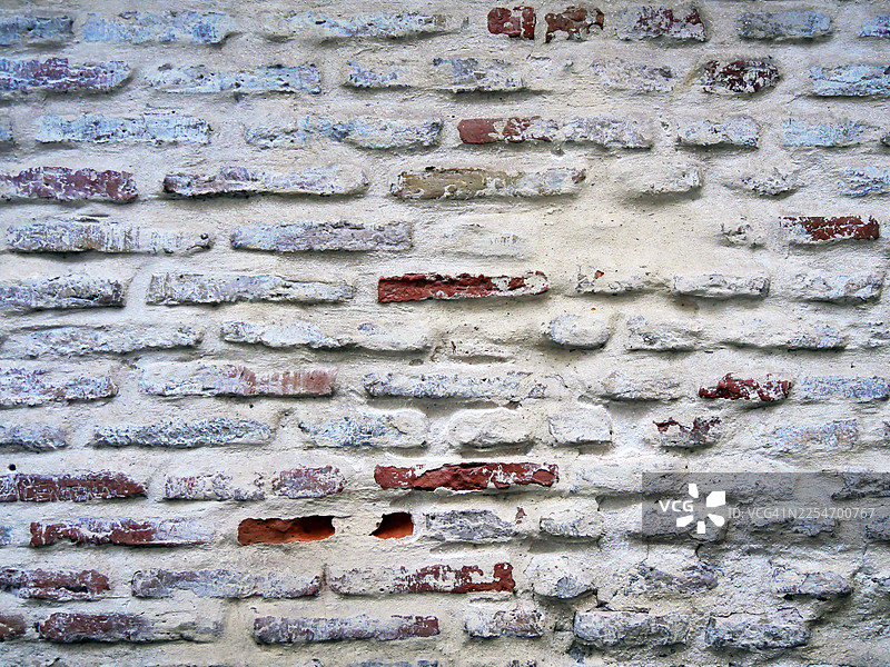 白色涂漆并带有铜绿的棕色砖墙特写，纹理粗糙。地点：西班牙塞维利亚。图片素材