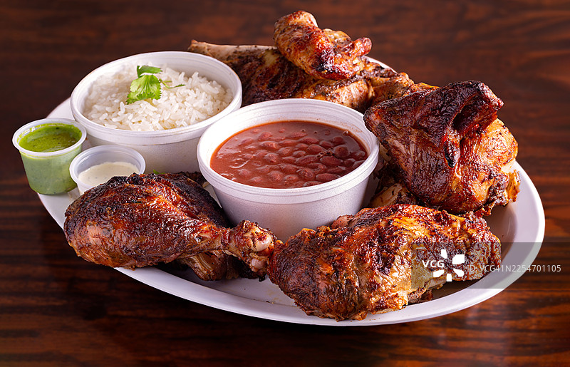 俯视角度拍摄的美味烤肉、米饭和豆子，盛放在餐盘上，旁边放着酱料，置于木桌上图片素材