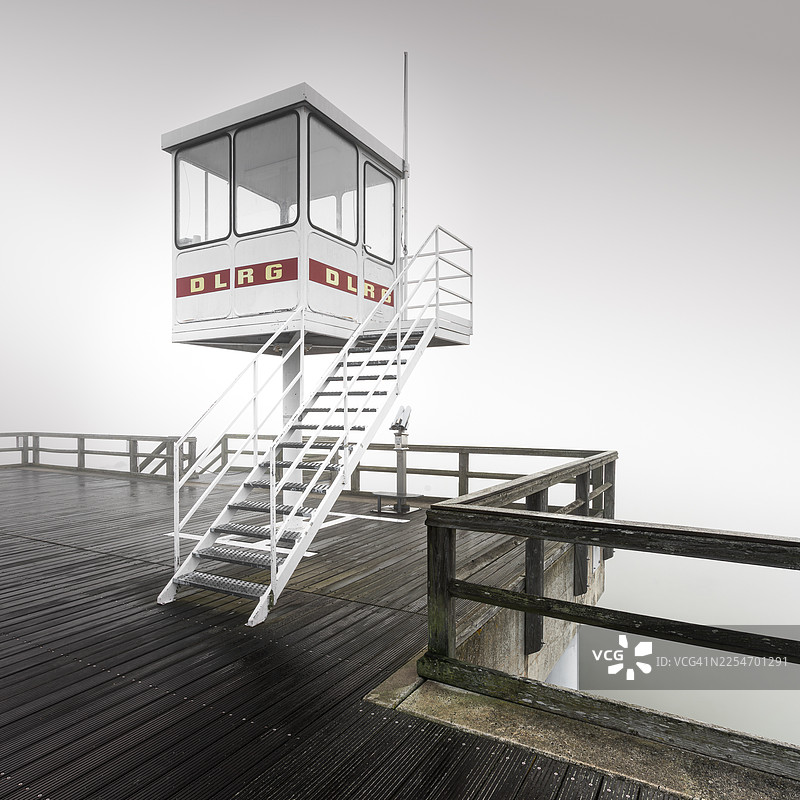 雾天里的救生员瞭望塔，一座码头延伸至迷雾之中，德国泽林图片素材