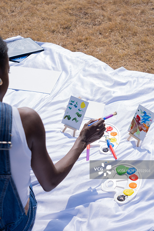 阳光明媚的日子里，一位创意女性在户外绘画，享受艺术与自然图片素材