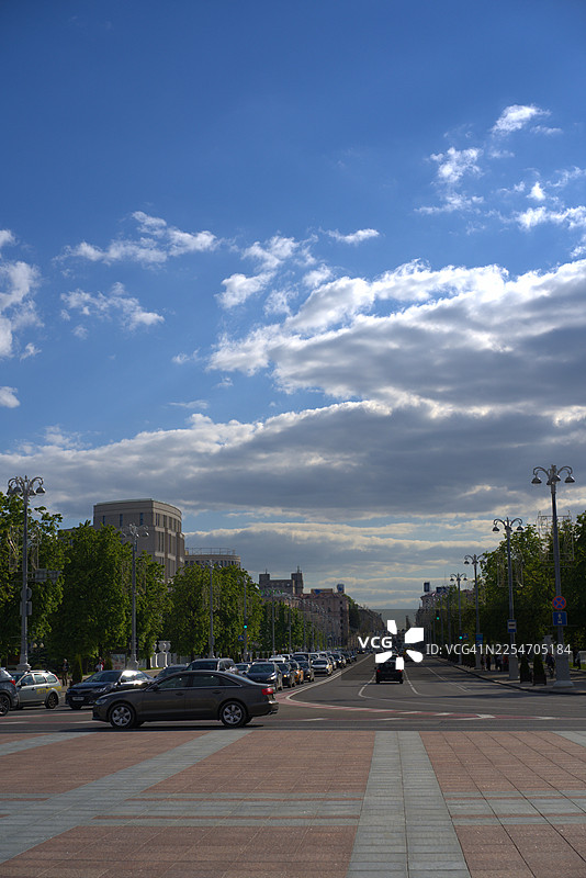 繁华的城市街道，车水马龙，高楼林立，天空云卷云舒，充满动感。图片素材