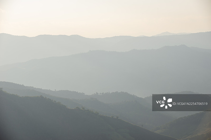 泰国清莱的 Doi Chang 山在薄雾中若隐若现，层叠的山脊线为高地景观增添了深度和氛围。图片素材