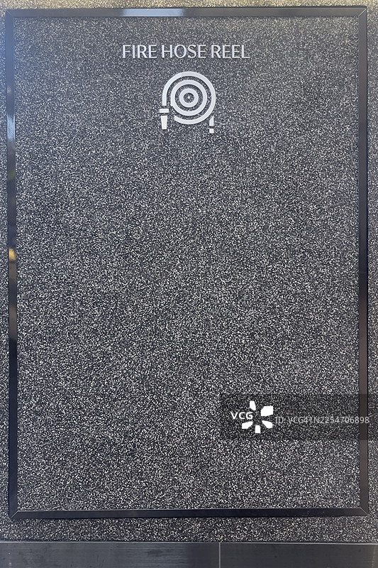 一个带有白色水龙带图标和文字的消防水龙带卷盘标识，背景为斑驳的灰色。图片素材