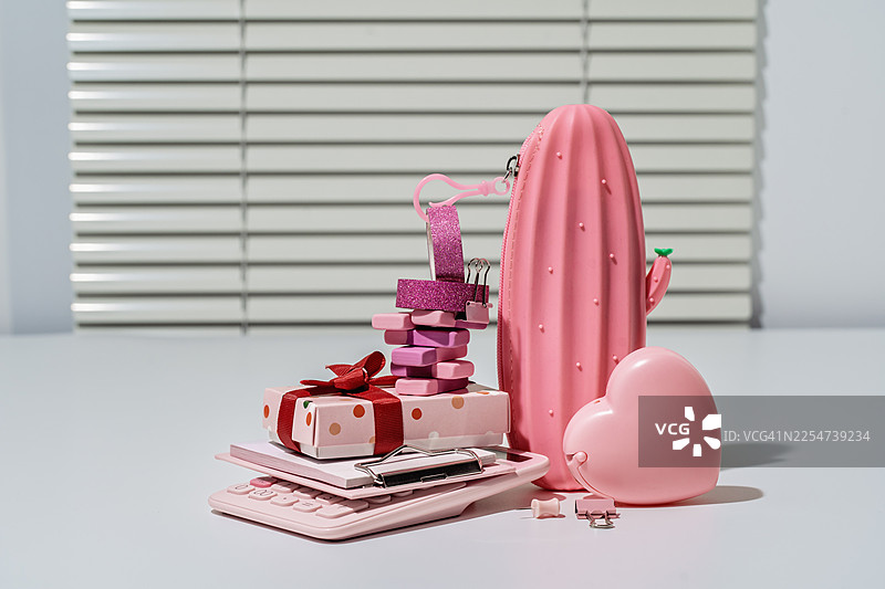 心形胶带座和其他粉色文具堆放在办公桌上图片素材