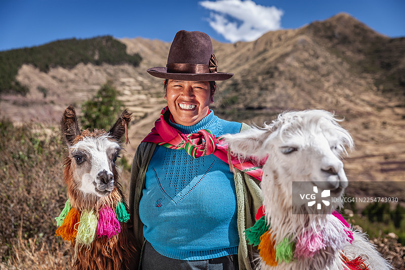 一位秘鲁妇女身着民族服装，在库斯科附近与羊驼合影图片素材