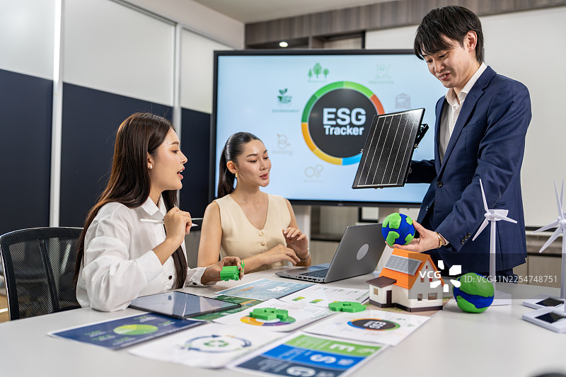 商界人士讨论ESG与太阳能电池板模型图片素材