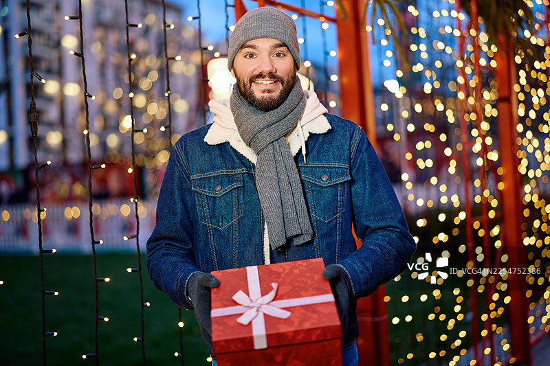 微笑的男人在户外展示圣诞礼物盒图片素材