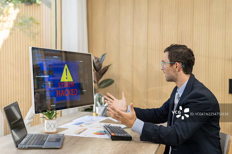 沮丧的商人在电脑屏幕上看到系统被黑客攻击的消息图片素材