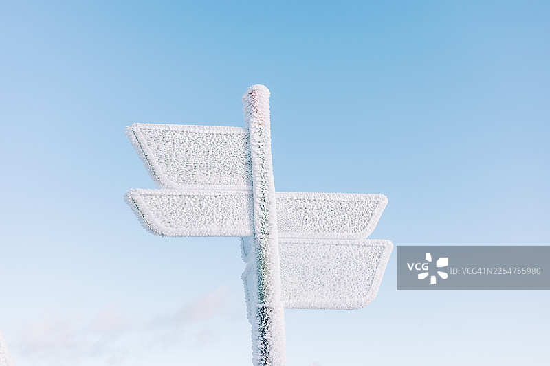 清晰的冬日天空下的霜冻路标：冰封的指示牌，冷冽天气摄影图片素材