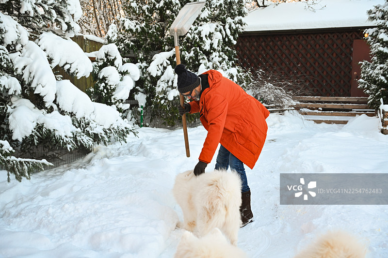 一位成熟的成年男子在花园里铲雪图片素材