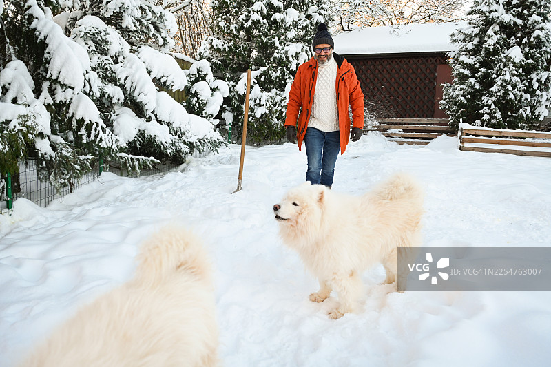 一位成熟的成年男性正在花园里铲雪图片素材