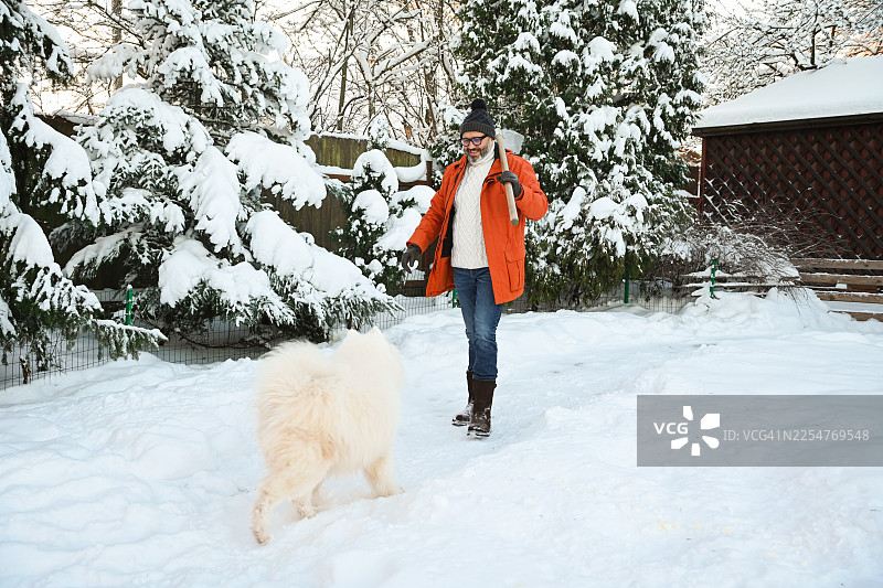 一名成熟的成年男子正在花园里铲雪图片素材
