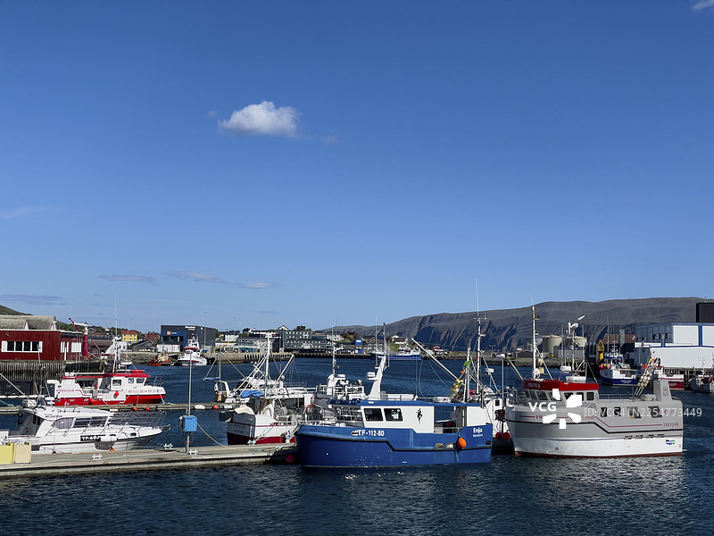 挪威芬马克郡巴特斯峡湾港口，晴朗的蓝天，背景有山脉，阳光明媚的渔船图片素材